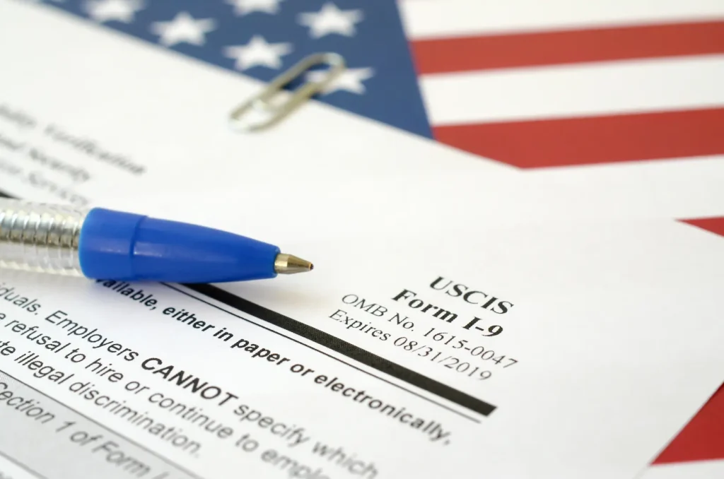 Close-up of USCIS Form I-9 with pen and American flag — I-9 verification service